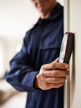 Pest control technician inspection moisture meter wall navy uniform, cropped worker checking damp surface in bright indoor light with blurred background and vertical copy space