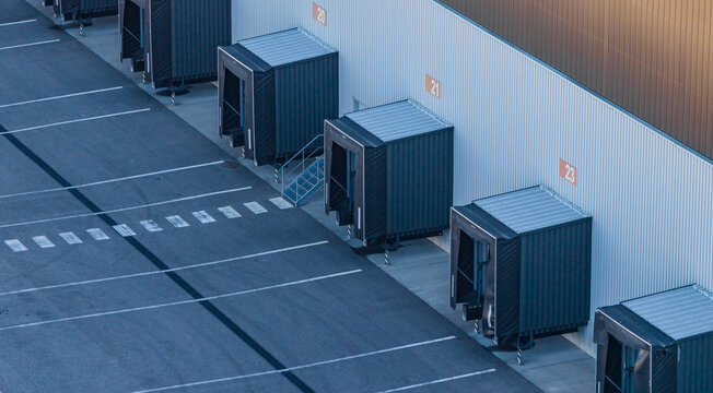 Aerial view of loading docks and empty truck bays at a large logistics warehouse and distribution center in Le Pouzin, Auvergne-Rhone-Alpes, France.