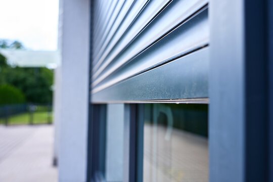 Partially lowered metal roller shutter above an exterior window. Concept of home shading