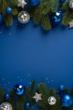 Blue holiday border with fir branches and ornaments for Merry Christmas and Happy New Year on vertical blue copyspace