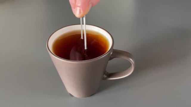 Dipping a Tea Bag into a Mug of Hot Water