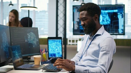 Fototapeta premium System administrator wears headphones and develops software with AI, debugging applications on a computer while listening to music during application testing.