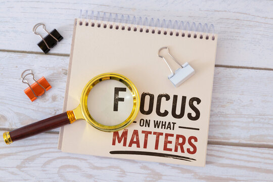Focus on What Matters Concept with Magnifying Glass on Notebook.
