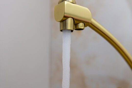 Golden Kitchen Faucet with Running Water, Modern Plumbing and Water Supply Concept.
