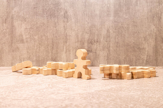 Wooden Human Figure Standing Among Puzzle Pieces - Individuality, Leadership and Teamwork Concept.