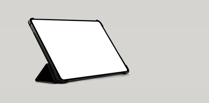 Empty tablet computer screen mockup with black case standing on light grey background