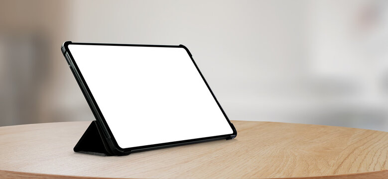 Tablet computer mockup propped on a wooden table in landscape mode with a blurred interior background