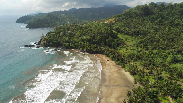 7 Ondas Beach, S&atilde;o Tom&eacute; and Pr&iacute;ncipe. Aerial view of parallel Atlantic waves reaching a wide sandy bay bordered by dense tropical forest and rolling green hills.Africa