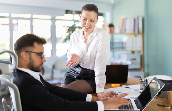 Portrait of adult business couple flirting at table at workplace in office