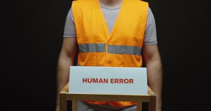 Worker holding a &ldquo;Human Error&rdquo; sign, representing workplace mistakes, operator errors, quality risks and manufacturing failures.