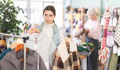 Armenian woman chooses winter and autumn clothes among jackets and coats in the store. Adult woman went shopping on a weekend © JackF
