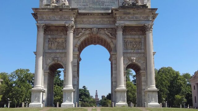 Majestic arco della pace, the arch of peace, zooming out to reveal the distant sforza castle, castello sforzesco, at the end of sempione park on a clear sunny day in milan, italy