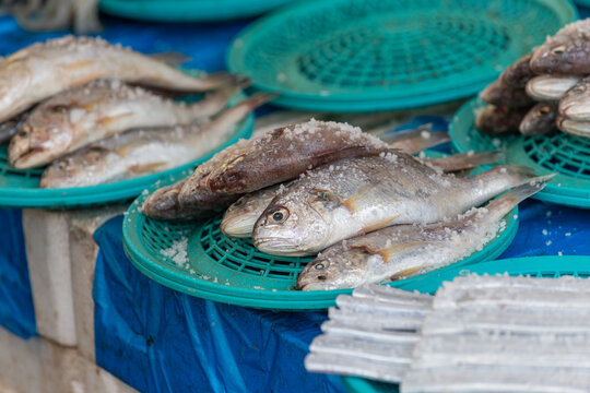 Salted hairtail and yellow croaker displayed in turquoise baskets at a traditional street market in South Korea.
