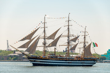 Amerigo Vespucci sails through New York Harbor on July 4. Italian Navy training ship carries dark sails, signal flags and an Italian flag over blue water. © white78