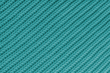Close up, macro of turquoise knitted fabric texture with visible diagonal yarn stitches and soft wool pattern. Cozy textile backdrop, cloth background, fashion wallpaper, winter clothing concepts © katyamaximenko