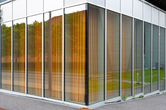Modern Glass Building Facade with Reflections and Vertical Blinds