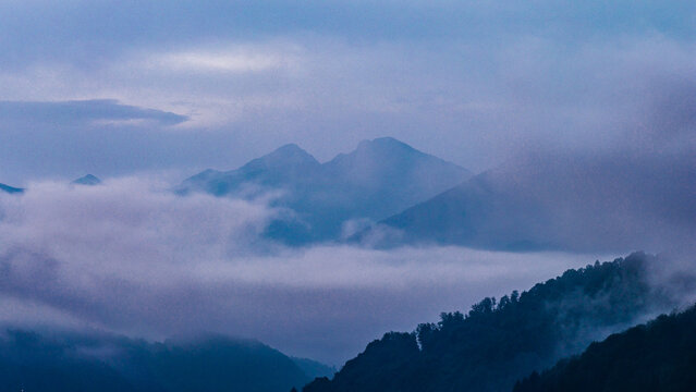 Aerial view of the misty mountains surrounding Lake Vidraru with dense forest slopes and low hanging clouds in the Fagaras Mountains, Arefu, Arges, Romania.
