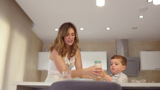 Caring mother preparing a baby bottle for her son at breakfast