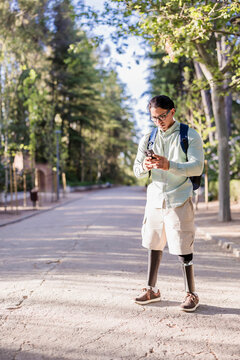 Latino man with prosthetic legs using smartphone in park