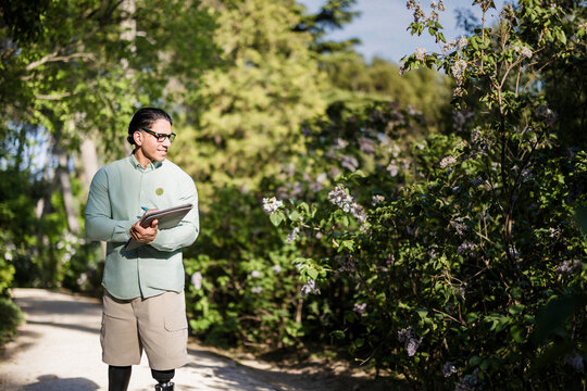 Latino biologist studying plants in a park
