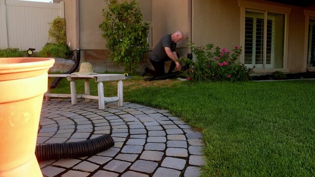 Wide view of a senior homeowner installing a downspout drainage system