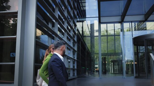 Diverse group of professionals arriving at a modern office, greeting coworkers, shaking hands and walking together. Corporate teamwork sequence showing inclusion, communication and collaboration