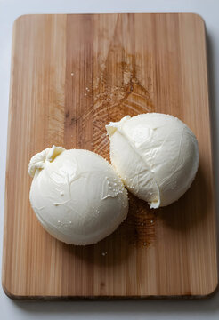Two fresh burrata cheese balls on a wooden cutting board, gourmet italian food ingredient for cooking and dining, the creamy dairy product is a popular choice for appetizers and meals