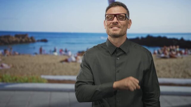 Man with glasses and fist extended toward camera performing a playful punch on a street promenade by the beach; confidence.