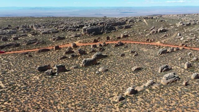 FPV aerial view of car driving in rocky desert through the arid landscape of Cederberg Municipality, Western Cape, South Africa.