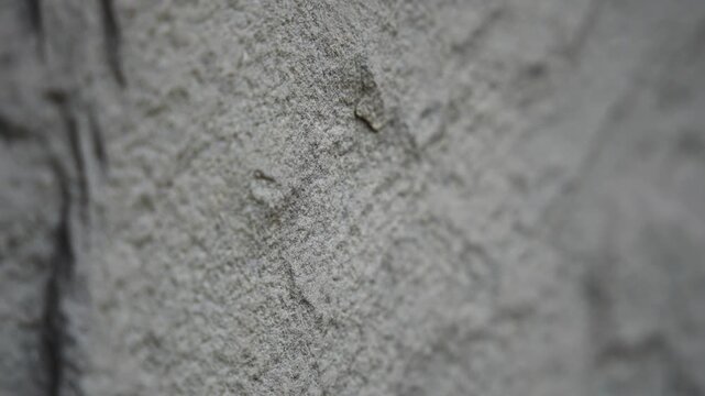 Slow horizontal camera pan from right to left showcasing the intricate details, roughness, and natural texture of a rugged stone surface.