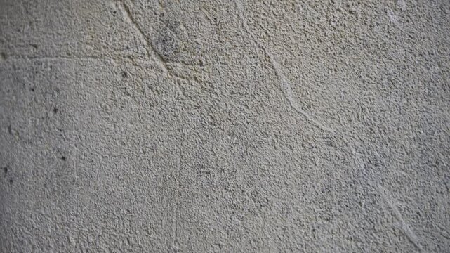 Slow horizontal camera pan from right to left showcasing the intricate details, roughness, and natural texture of a rugged stone surface.