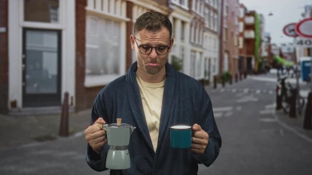 Man in robe holds stovetop coffee maker and teal mug, pouting with visible hands on street; weary morning.