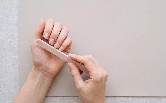 Woman filing her fingernails with an emery board nail file for manicure and beauty care