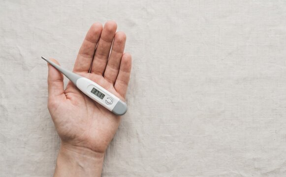 Person holding a digital thermometer showing normal body temperature for health and medical care