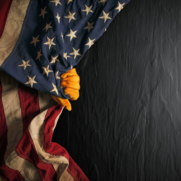 Worn work glove pulling back the American flag. Symbolic of blue collar workers, USA manufacturing, pride in products Made in United States of America, or to celebrate Father's day or US Labor Day.