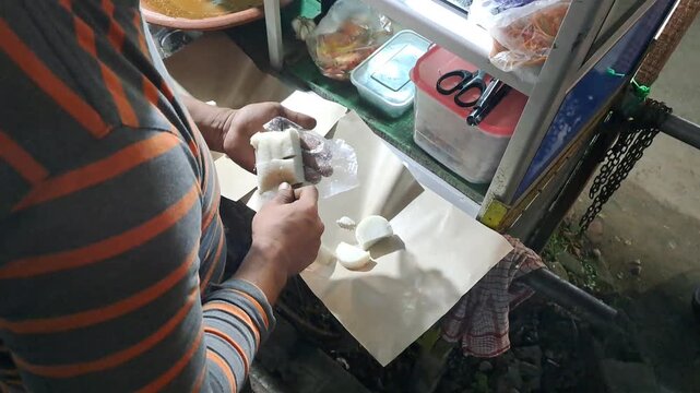 Street food vendor preparing Tahu Tek, a traditional East Javanese dish. Close up of cutting fried tofu, omelet, rice cakes using scissors, mixing rich peanut sauce. SUMENEP, INDONESIA - MAY 27, 2026