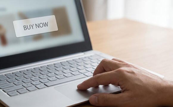 Person using a laptop with a buy now button on screen for online shopping and ecommerce transactions