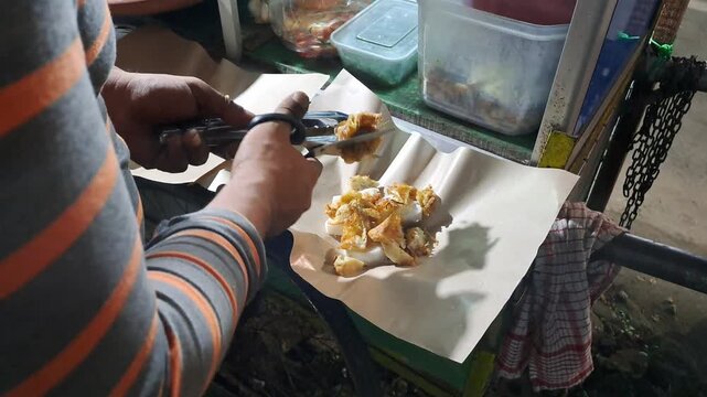 Street food vendor preparing Tahu Tek, a traditional East Javanese dish. Close up of cutting fried tofu, omelet, rice cakes using scissors, mixing rich peanut sauce. SUMENEP, INDONESIA - MAY 27, 2026