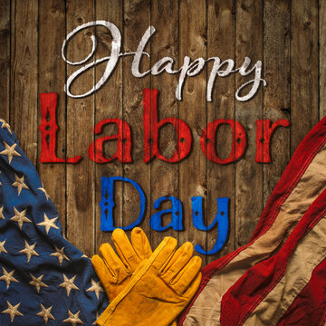Patriotic Happy Labor Day text with worn work gloves and the USA flag on wooden background. Symbolic of the American labor movement and pride in America's blue collar workers. Celebrate US Labor Day.