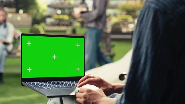 Isolated chroma key laptop mockup appears as a student uses the trackpad outdoors on campus, with copy space for editable screen replacement.