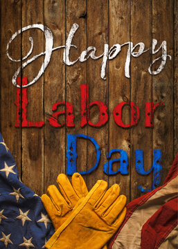 Patriotic Happy Labor Day text with worn work gloves and the USA flag on wooden background. Symbolic of the American labor movement and pride in America's blue collar workers. Celebrate US Labor Day.