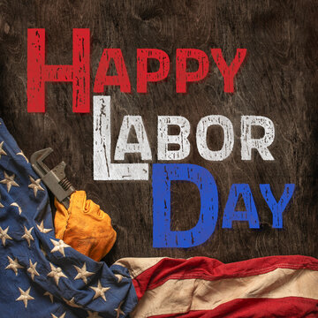 Patriotic Happy Labor Day text with worn work glove and the USA flag on wooden background. Symbolic of the American labor movement and pride in America's blue collar workers. Celebrate US Labor Day.