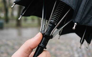 Fototapeta premium Close-up of an automatic folding umbrella mechanism with spring and metal ribs being held by a hand