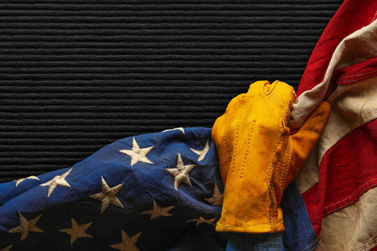 Work glove pulling back the American flag over an empty felt board with space for text. Symbolic of blue collar workers, pride in American manufacturing or products Made in USA, or for US Labor Day.