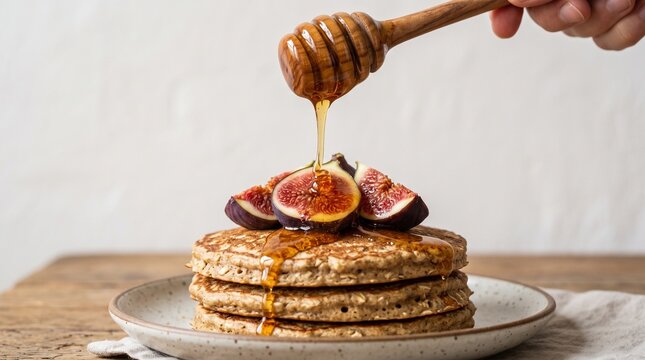 Stack of healthy oat pancakes drizzled with honey and topped with fresh figs
