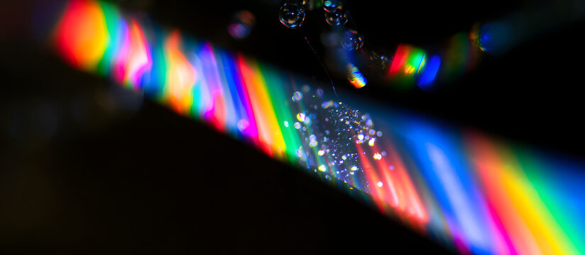 A detailed look at a vivid rainbow diode laser illuminating nucleic acids, accompanied by shimmering nanoparticles, set against a dark backdrop