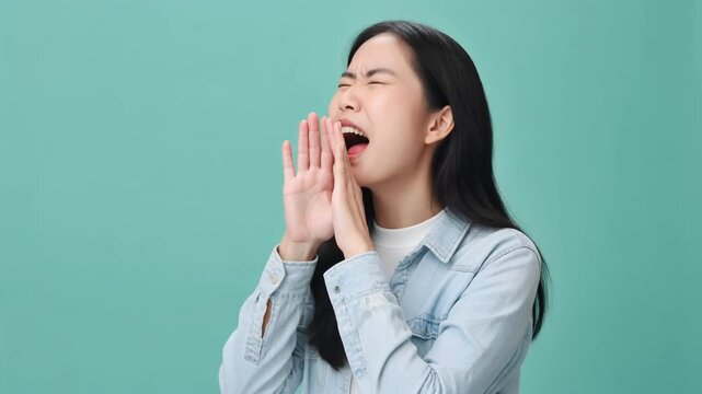 ミント色の背景で20代後半の女性が両手を口元に添え目を閉じて横方向へ全力で叫ぶ