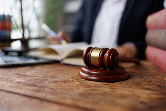 Legal professional studying law books and documents, gavel on desk symbolizing justice and authority in courtroom