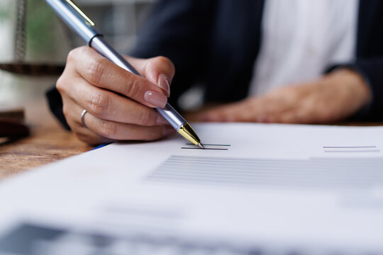 Person signing a legal contract, agreement, or important business document with a pen, confirming partnership or deal