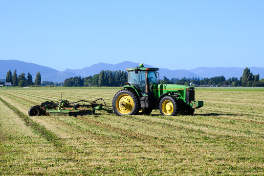 Mount Vernon, WA, USA - August 8, 2026; John Deere 8300 row crop tractor with 5026 Schulte rotary cutter in mowed field